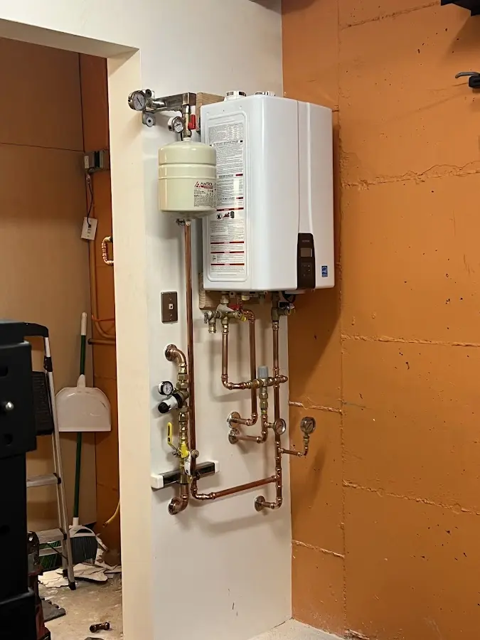 Plumbing technician inspecting water heater connections in Dundee